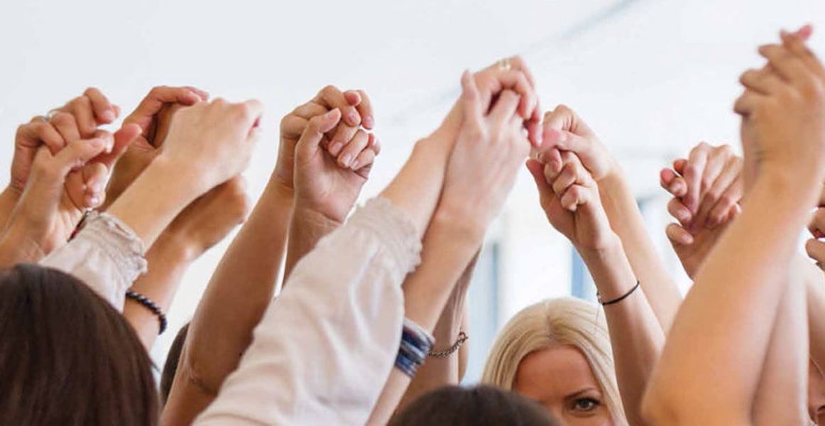 Photo of a group clasping hands, showing support