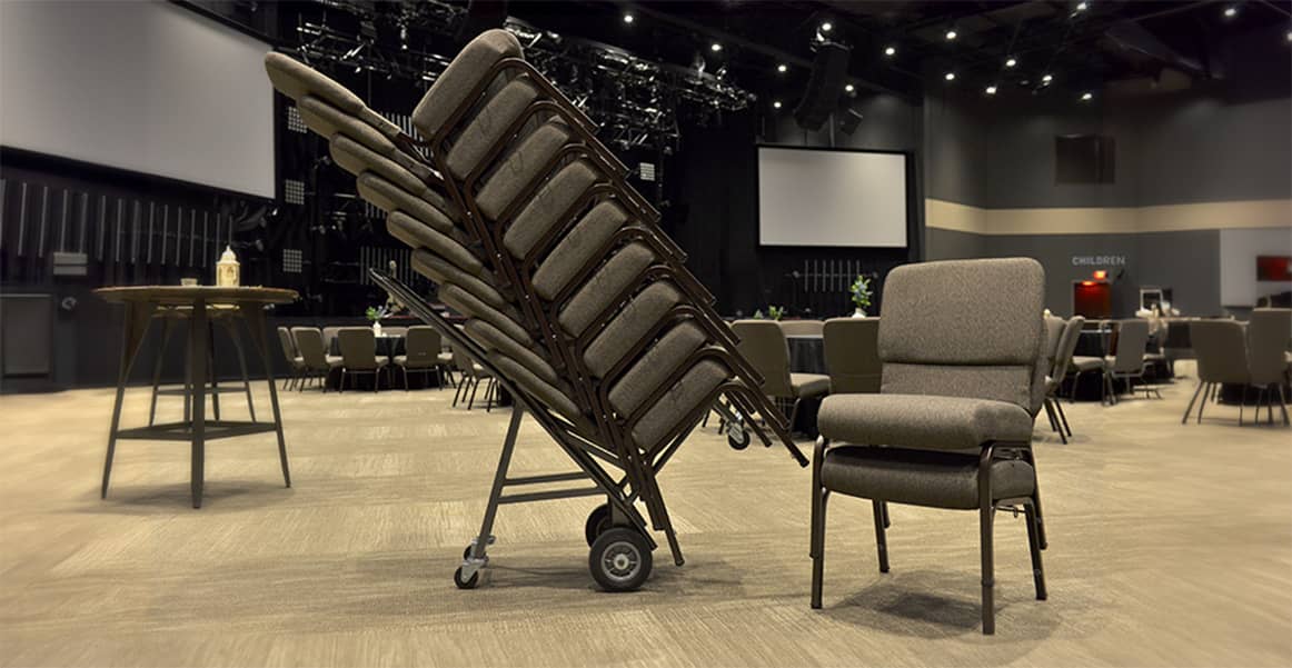 Bertolini chairs stacked on a cart in a large church hall