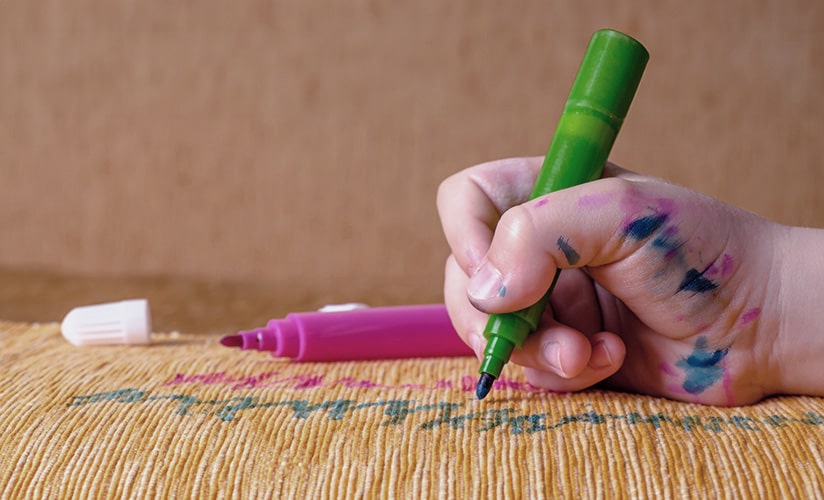 close-up of a child coloring on furniture with markers