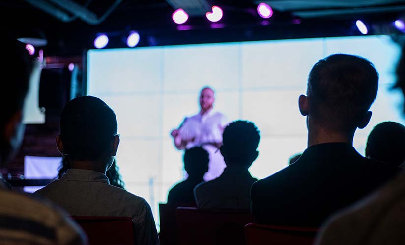 Silhouetted crowd with a stage presentation in the background