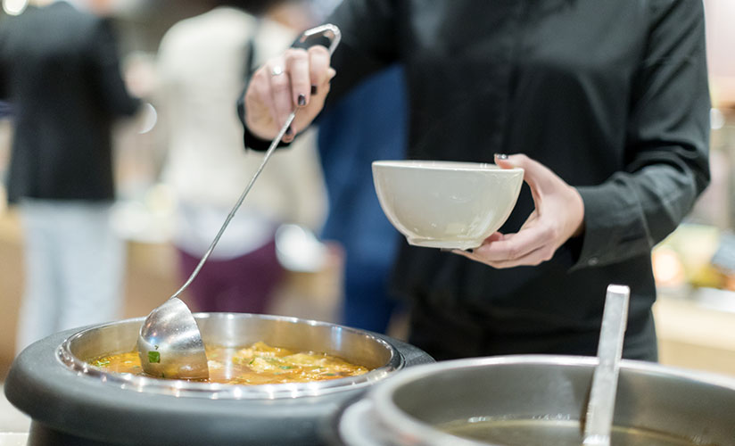 primo piano di una persona che versa la zuppa in una ciotola