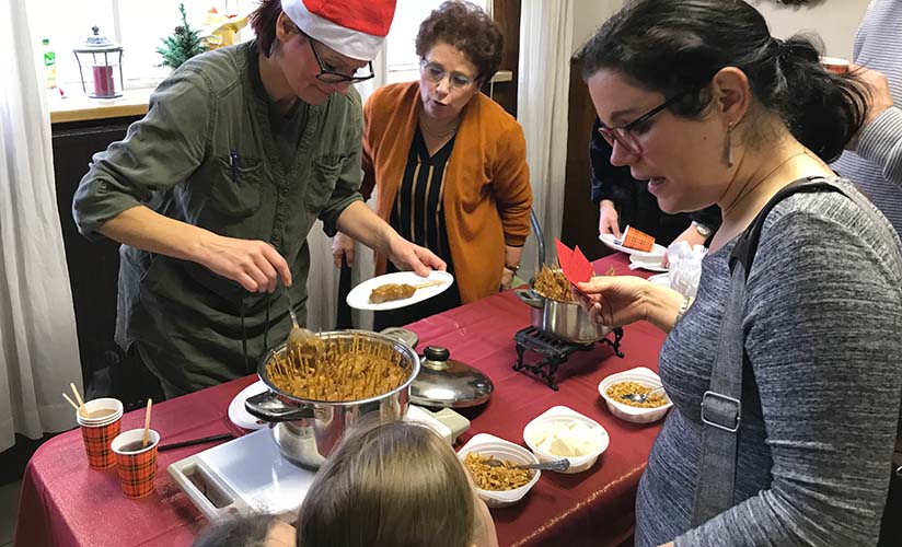 i partecipanti all'evento prendono cibo a un tavolo in stile potluck