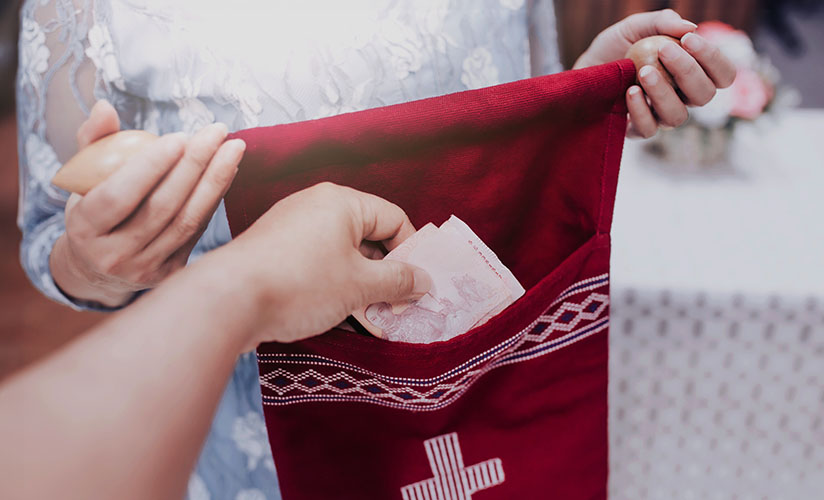 A close up of a person placing money into a collections bag