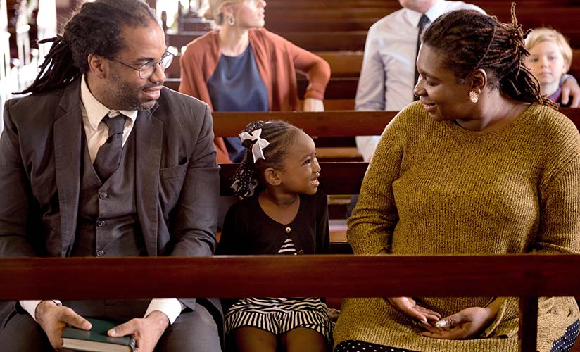 Millennial family with a young child all seated in a pew