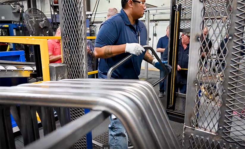 Employees preparing shaped metal frames for the next step of the manufacturing process