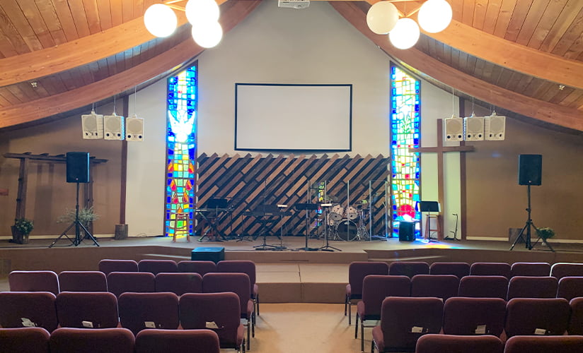 A warm local church hall with chairs facing a well-lit stage.