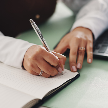 Close up image of hands writing in a notebook