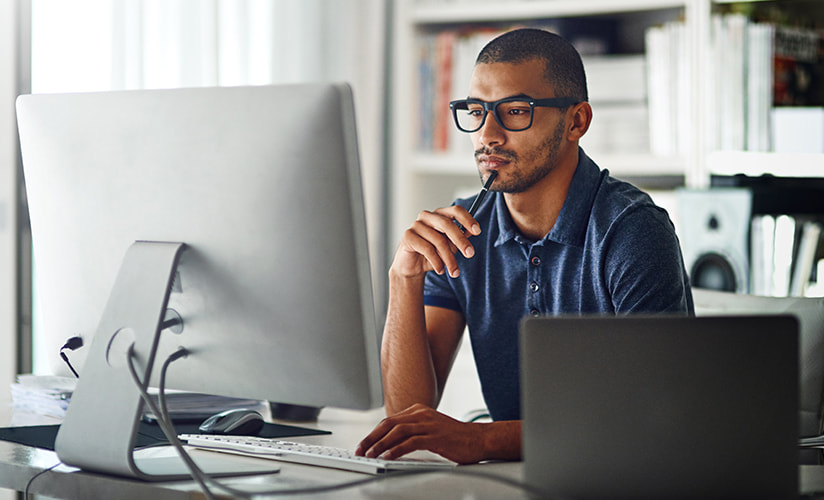 Man at his computer, thinking.
